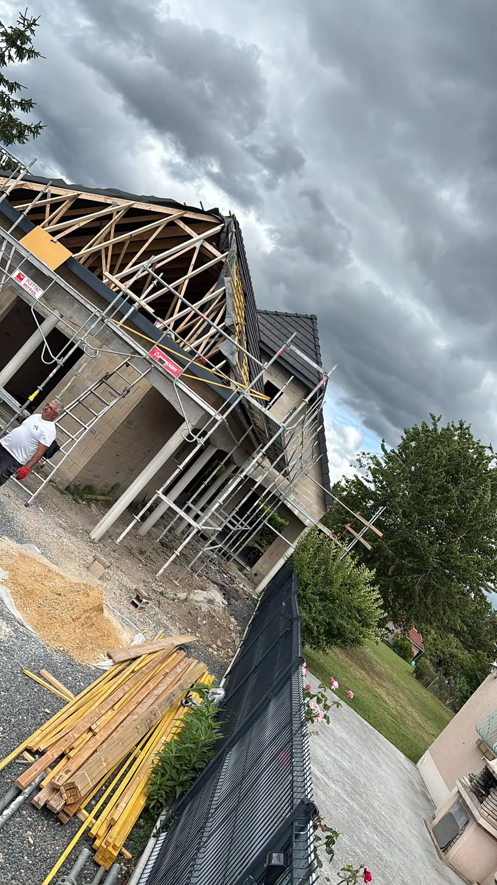 Vue en contre-plongée d’une charpente en cours de montage sous un ciel gris