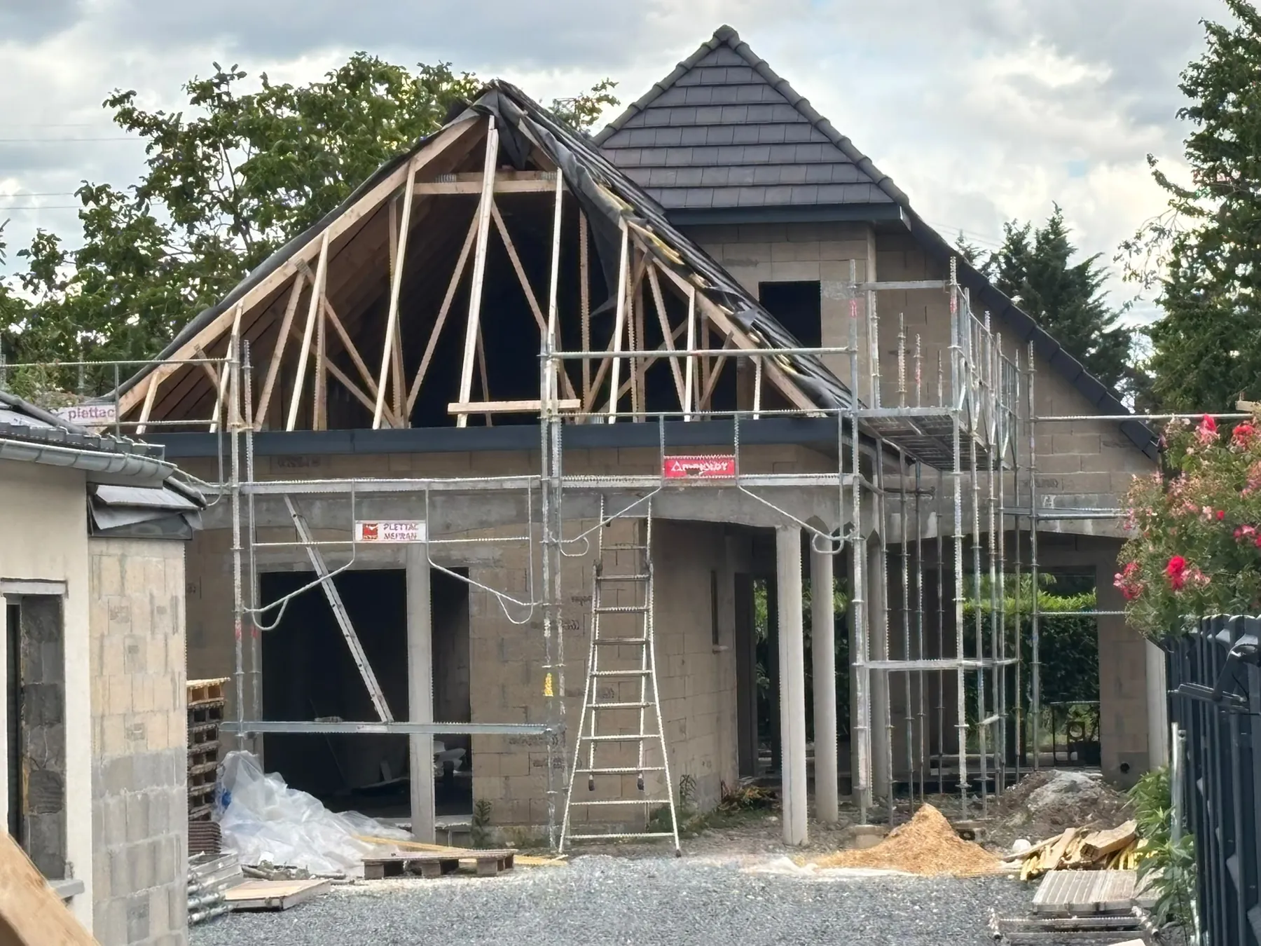 Charpente en fermettes de bois clair au-dessus d’une maison en travaux