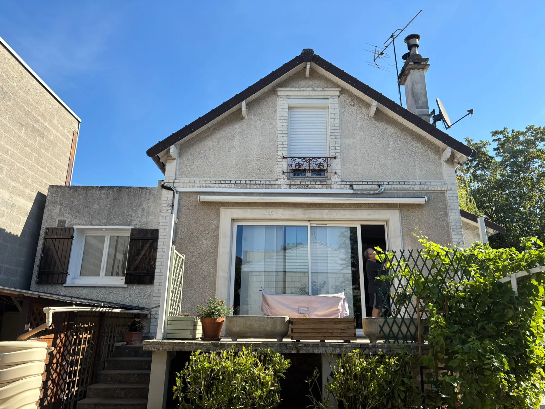 Maison à la façade grise et terne, terrasse en bois au premier plan