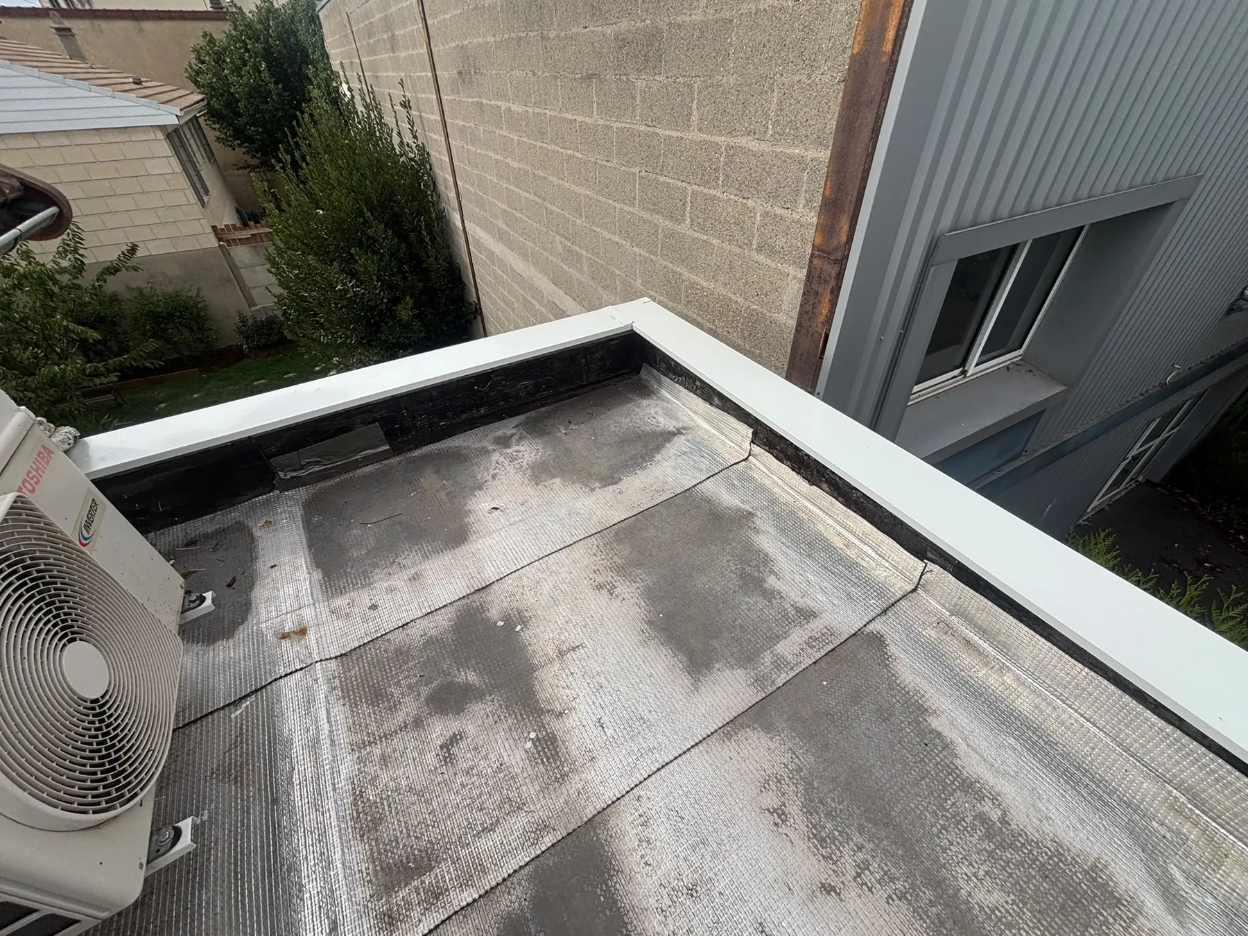 Toit-terrasse au revêtement gris bordé de sa couvertine